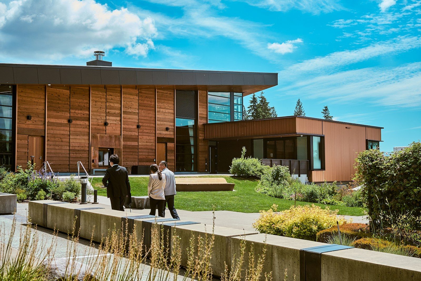 Modern building with people walking in landscaped outdoor area.