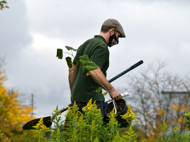 a man in a green shirt holding a pair of gardening tools