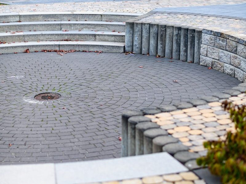 Curved paved seating area with stone steps and greenery.