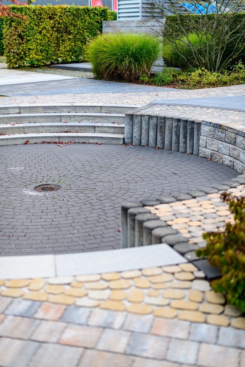 Curved paved seating area with stone steps and greenery.